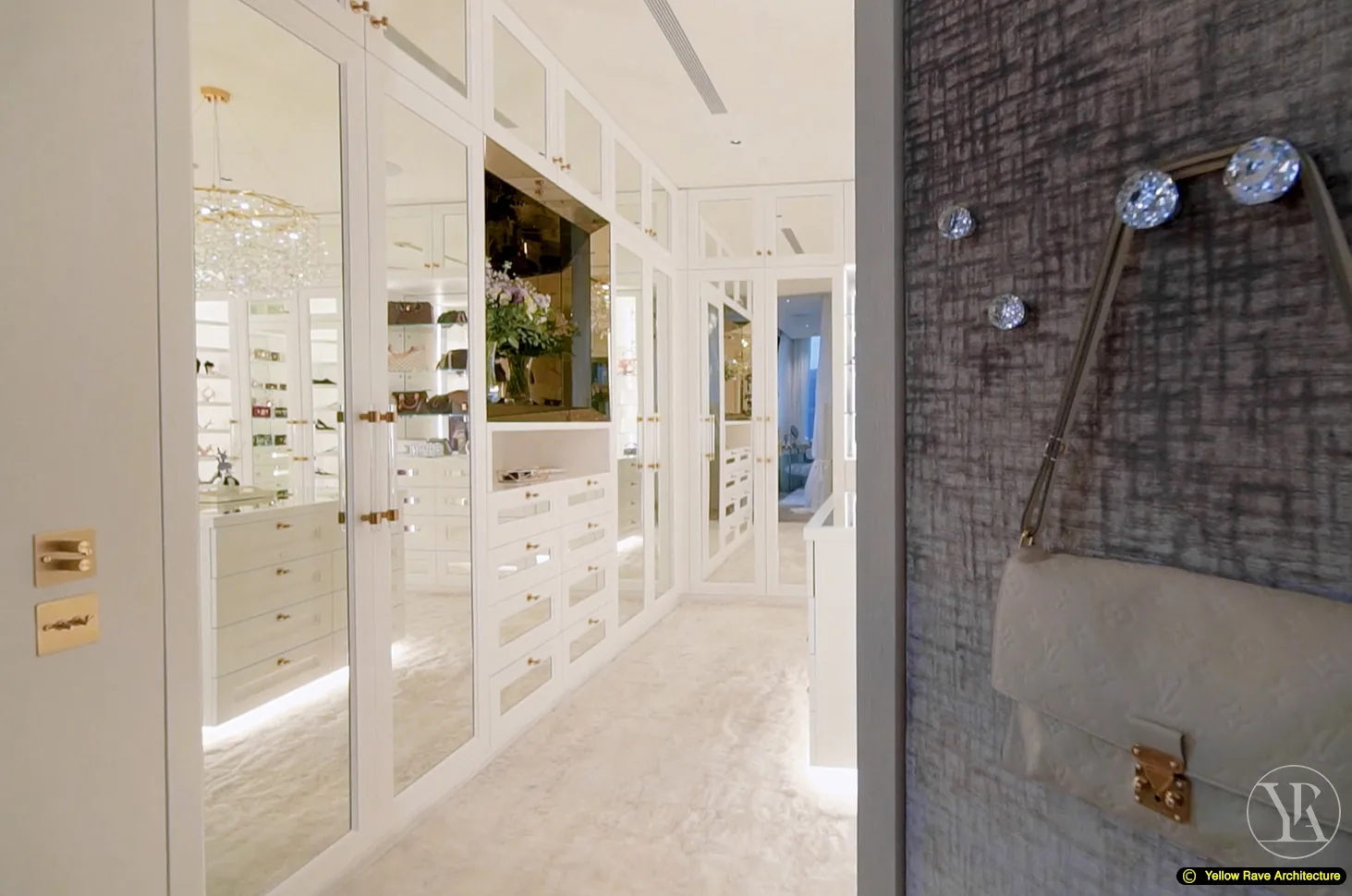 Show-Piece Wardrobe — view from corridor entry showing handbags displayed on crystal hooks against textured grey wall, white mirrored wardrobe interior visible through doorway