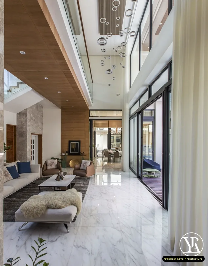 Coastal Courtyard Residence — double-height living area with globe cluster pendant, white marble floor and full-height glazing to the pool terrace