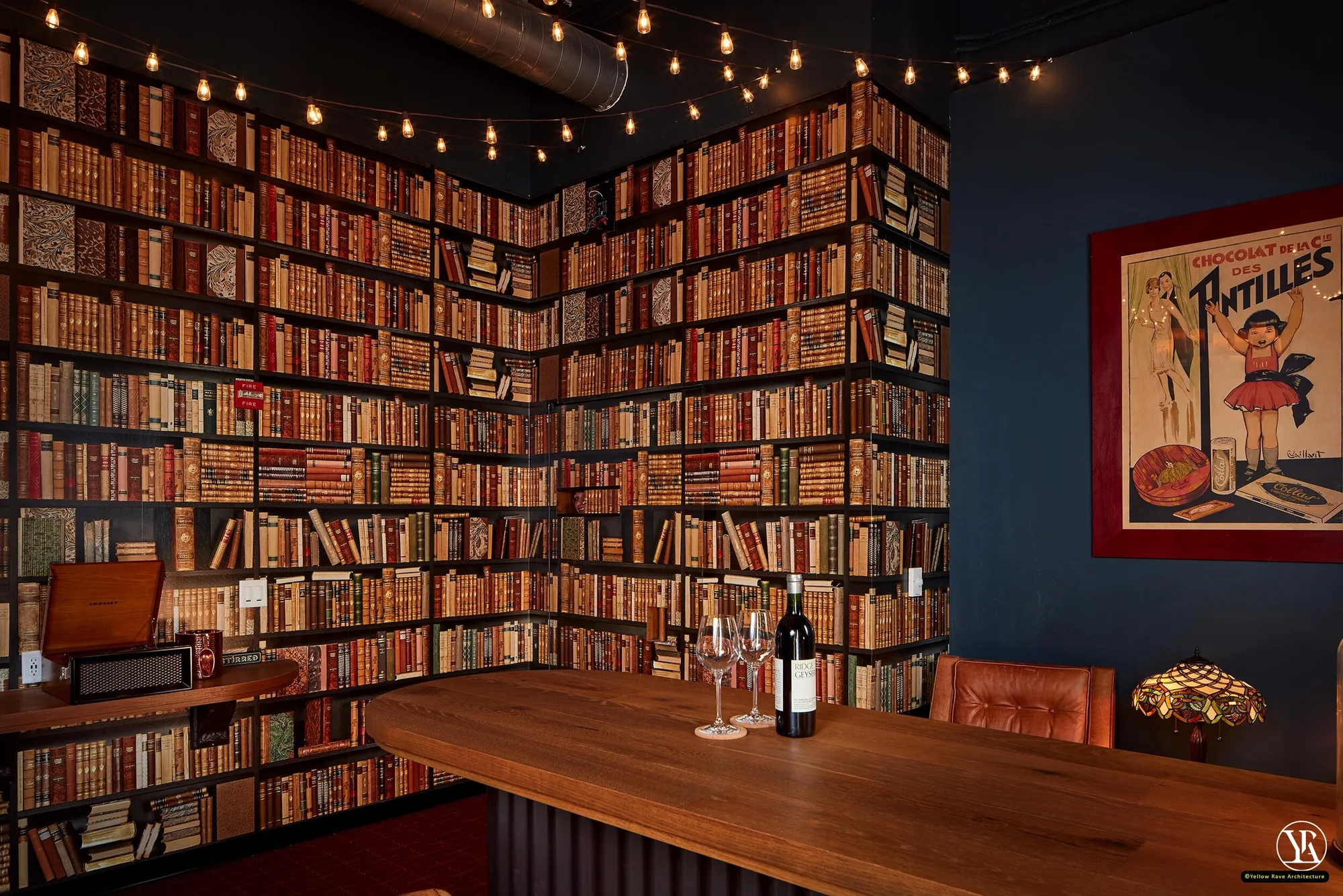 Man Cave — inner bar room with floor-to-ceiling leather-bound books, flat timber bar counter, Tiffany lamp and vintage French advertising poster