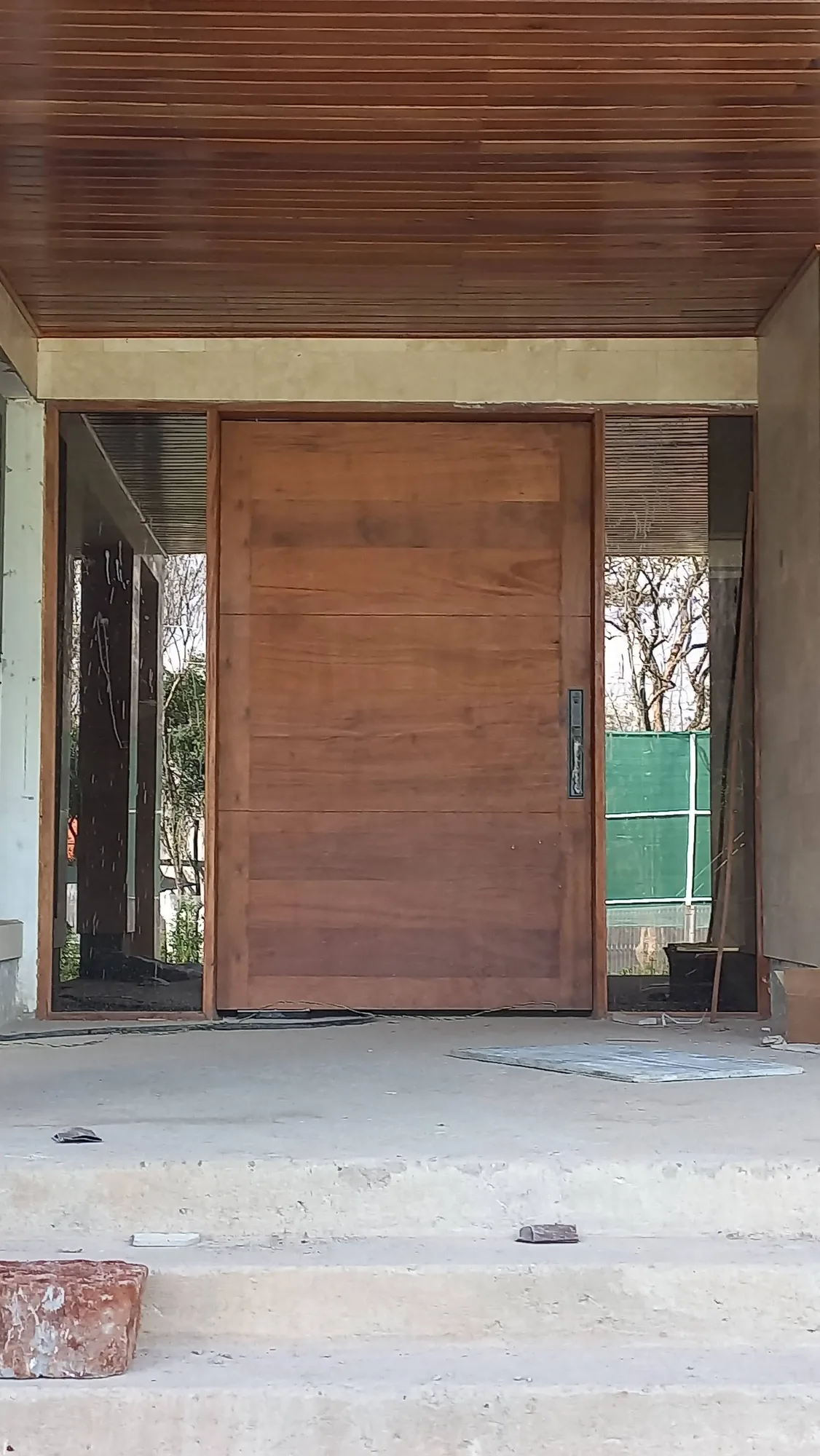 House of Wood and Marble — exterior stone cladding detail showing two-tone sandstone and travertine coursing with water feature plinth
