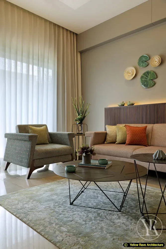 Earth Tone — living room with blush sectional sofa, orange accent cushions, circular metal coffee table and ceramic lotus wall installation