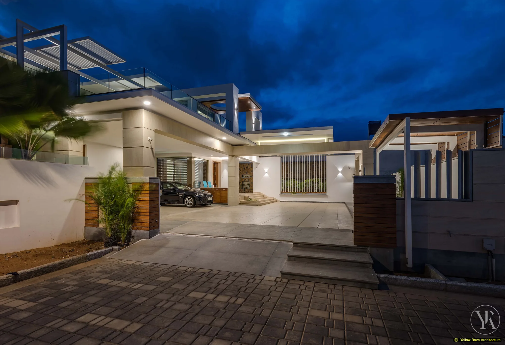 Nyali Residence — landscaped courtyard garden with row of potted bamboo along a white vertical-batten screen wall, entry steps and timber-framed front door