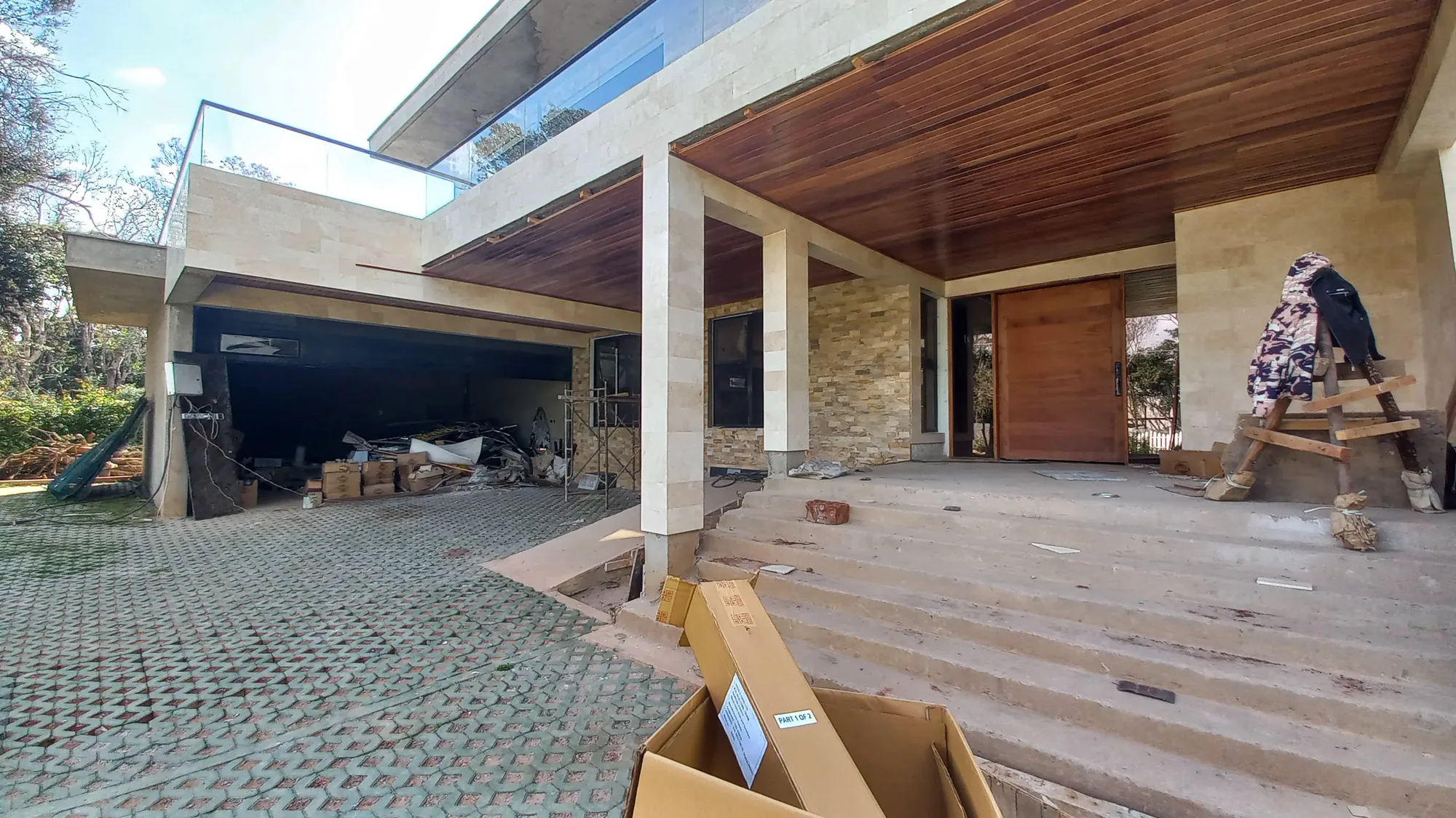House of Wood and Marble — construction site view showing stone cladding work in progress on the main facade