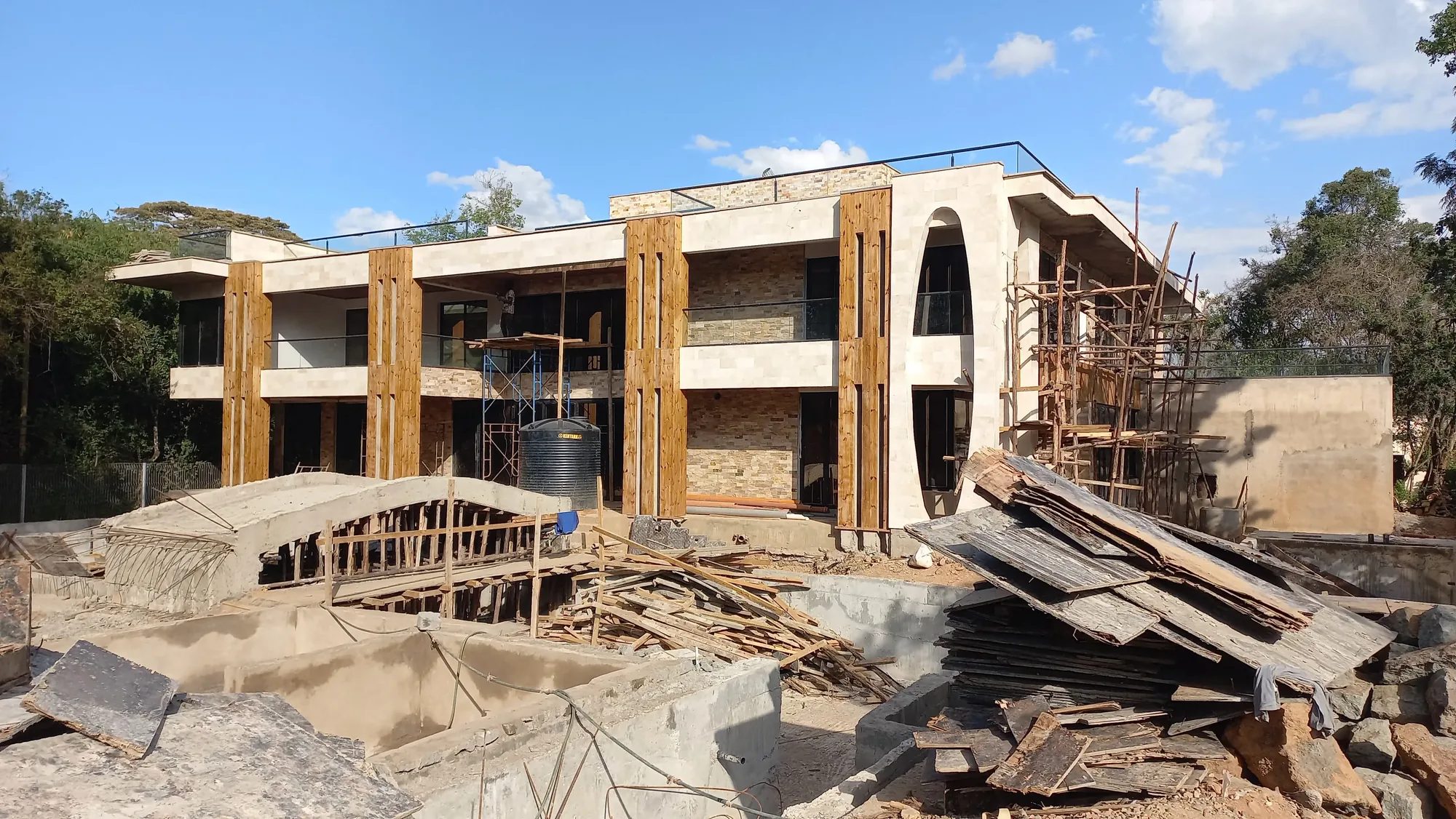 House of Wood and Marble — interior construction showing concrete structure with stone and timber cladding works in progress