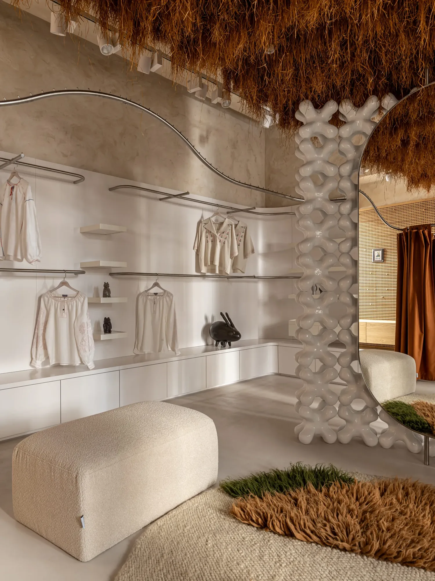 Miko Heritage Boutique — clothing rails and shelving wall with sculptural mirror detail