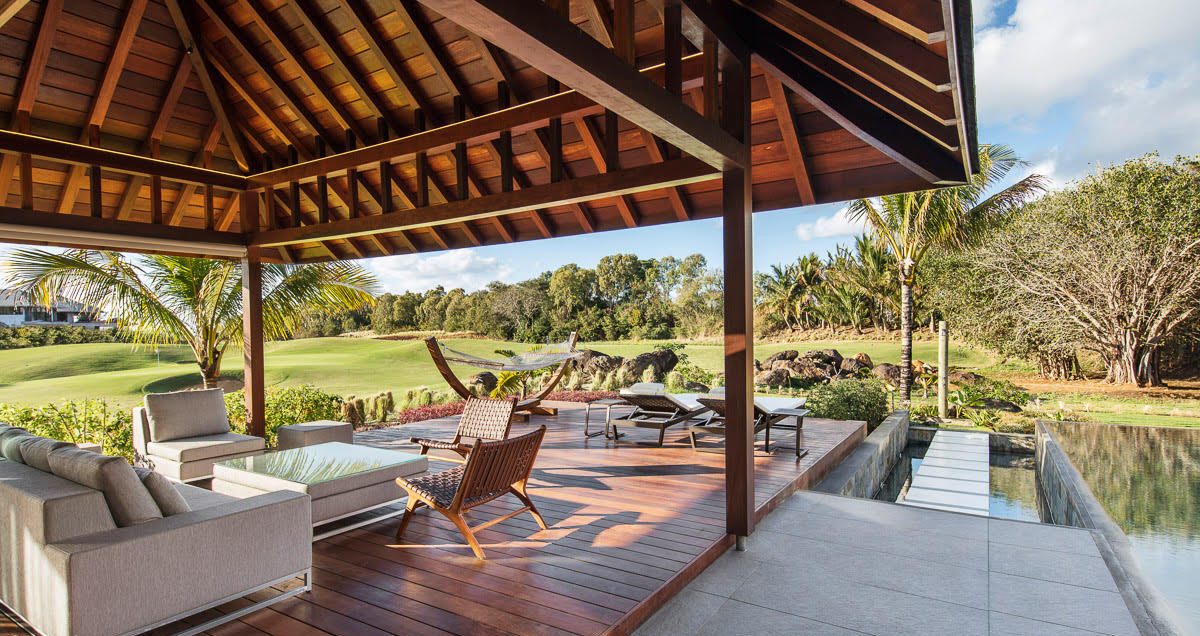 Serenity Abode — open-plan living room with exposed timber rafter ceiling and glass walls to the pool deck