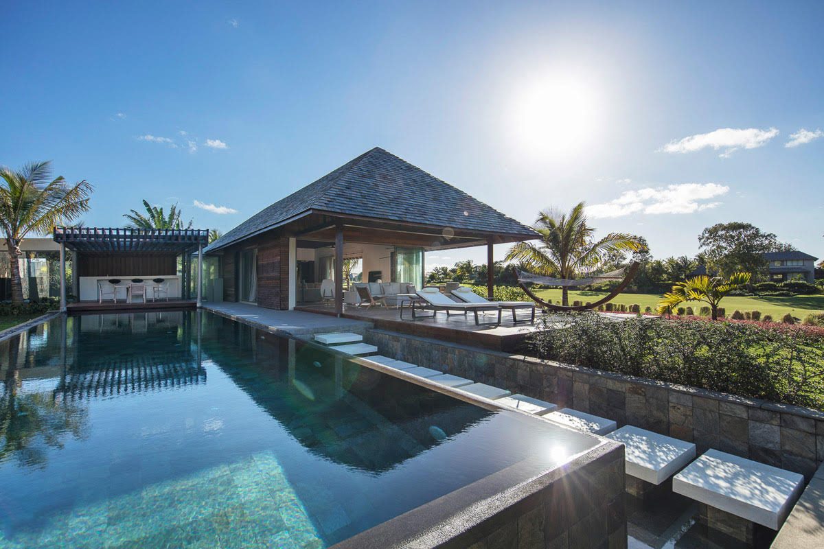 Serenity Abode — night view of both pavilions with lap pool lit between them and tropical setting beyond