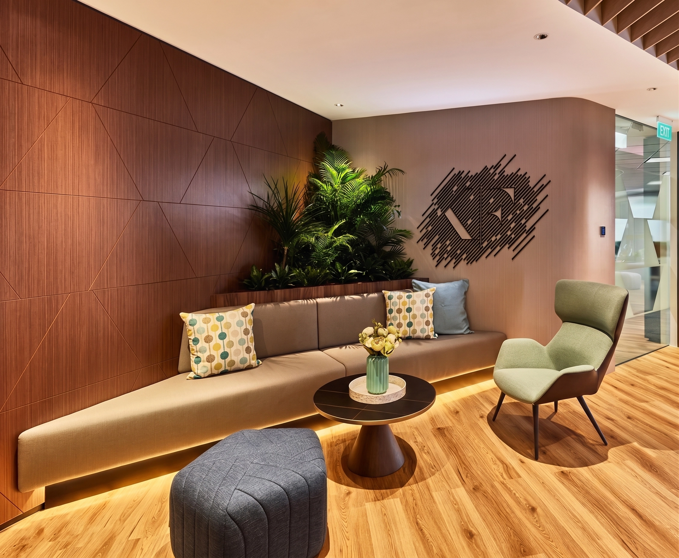 Quiet lounge with a long beige bench, green armchair, timber walls, and a planted recess